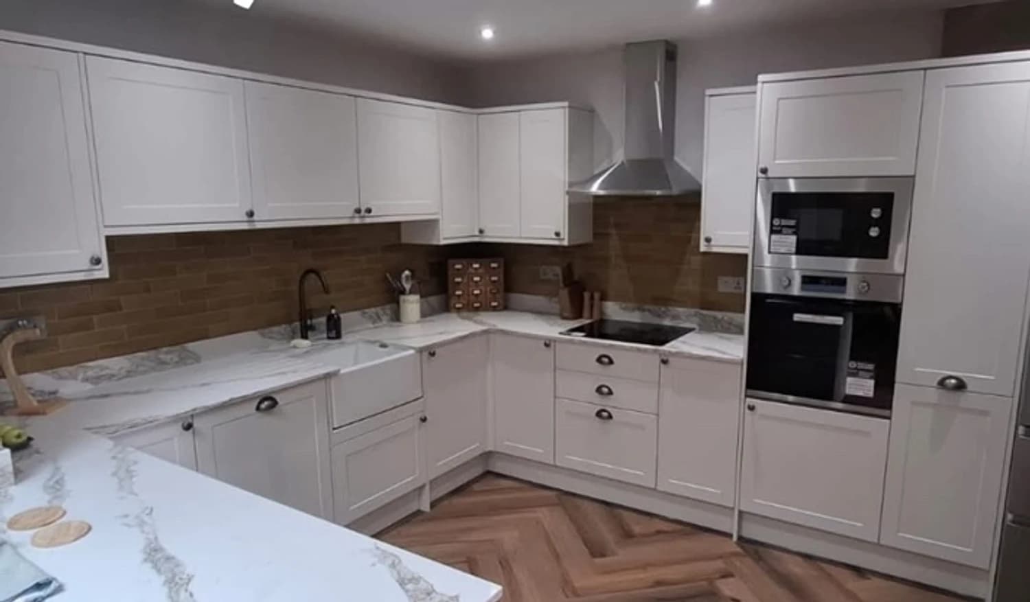 Finished shaker-style kitchen with marble-effect worktops and herringbone oak flooring