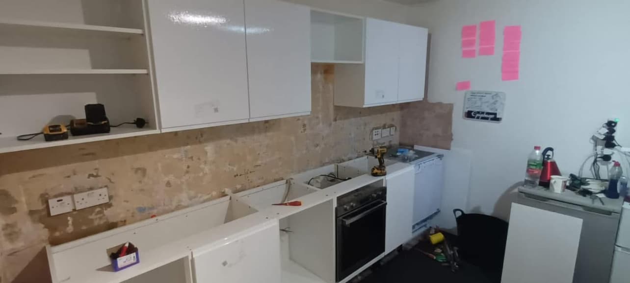 Before — kitchen mid-installation with bare plaster walls
